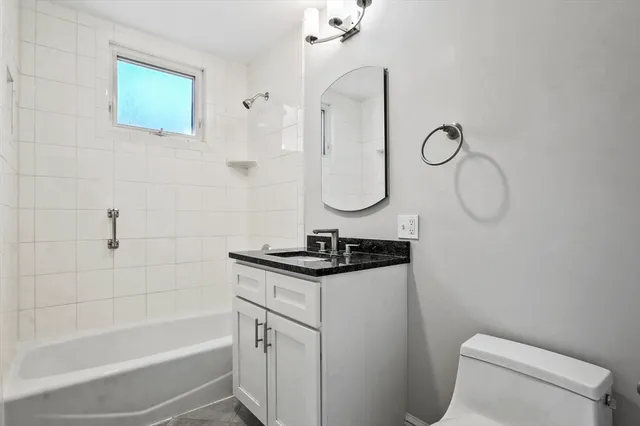 a bathroom with a granite countertop sink a toilet and shower
