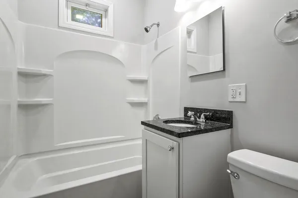 a bathroom with a granite countertop sink and a toilet