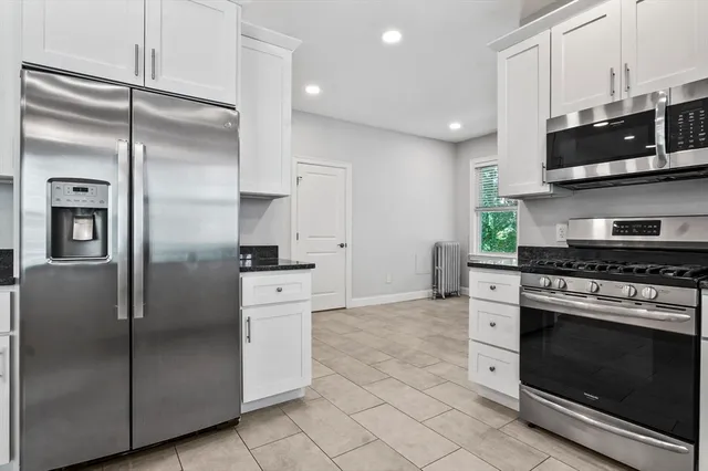 a kitchen with stainless steel appliances granite countertop a refrigerator a stove and a sink with wooden floor