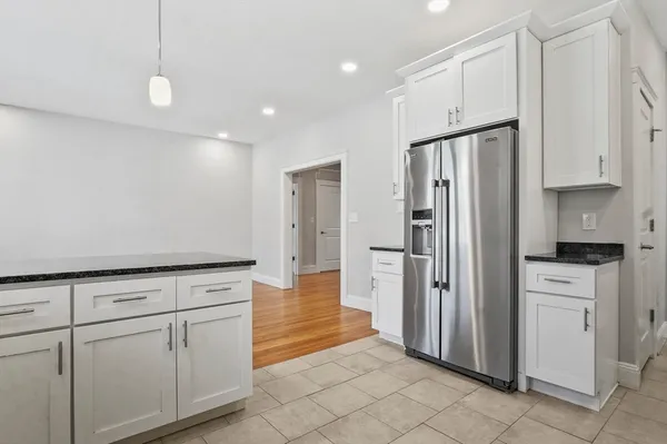 a kitchen with white cabinets and refrigerator