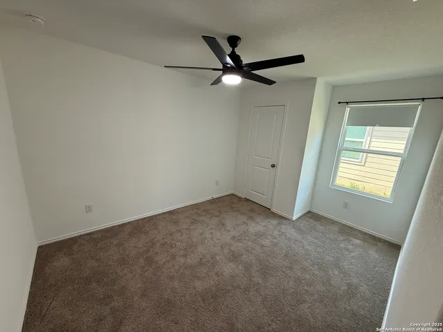 an empty room with a window and a fan