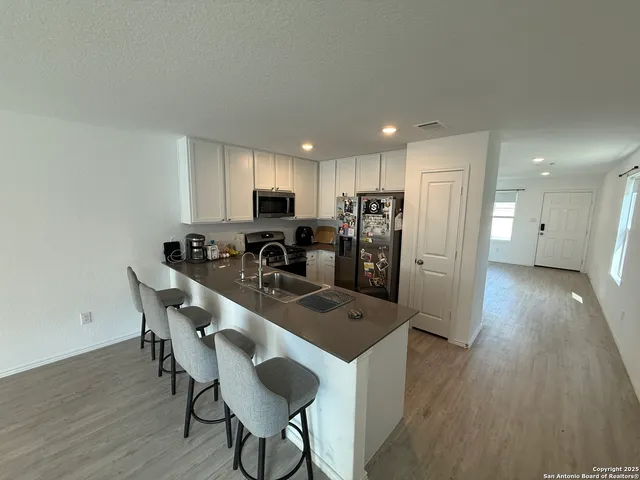 a kitchen with stainless steel appliances a refrigerator a stove a sink dishwasher and a microwave with wooden floor