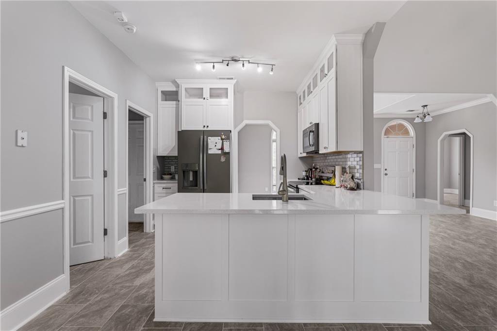 1449 Cummings Road Smiths Station, AL 36877 - Photo 15 of 28 Bright kitchen featuring white cabinetry, a spacious island with a sink, stainless steel appliances, and wood-finish flooring