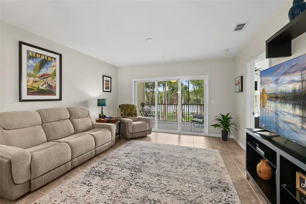 a living room with furniture floor to ceiling window and a flat screen tv