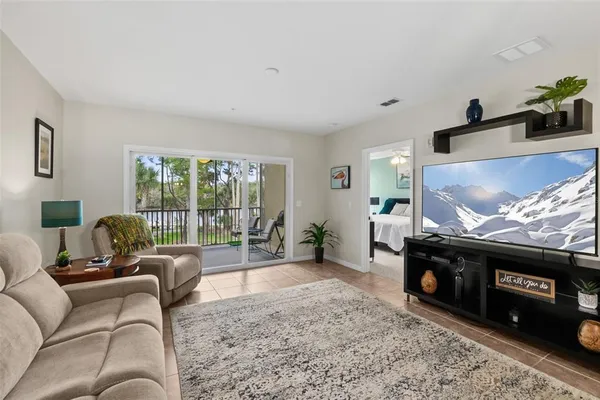 a living room with furniture a flat screen tv and a floor to ceiling window