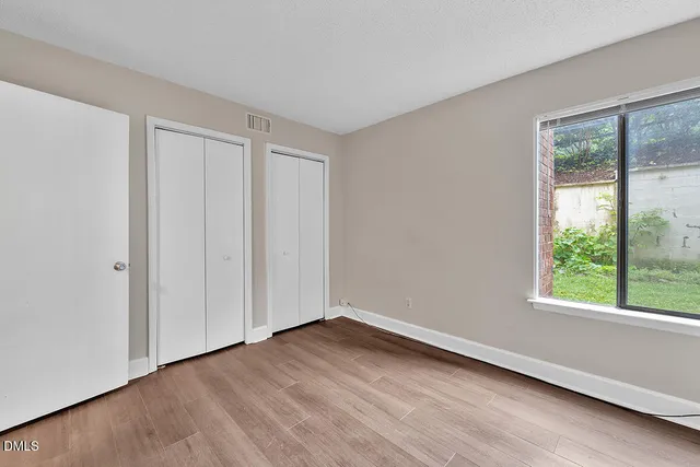 a view of an empty room with wooden floor and a window