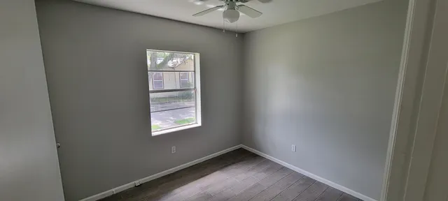 an empty room with windows and fan