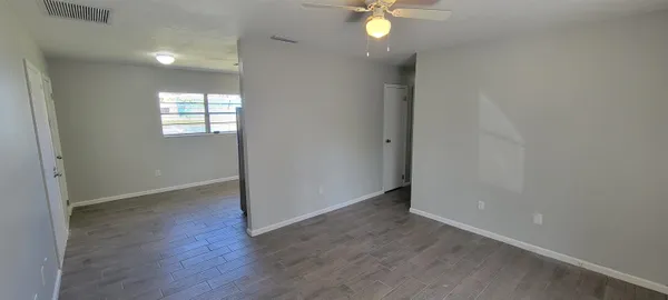 an empty room with wooden floor and windows