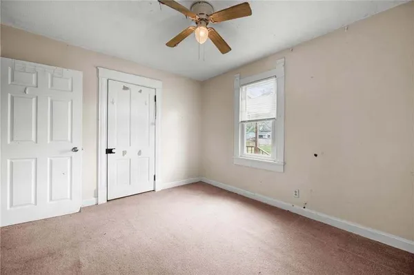 an empty room with chandelier fan and windows