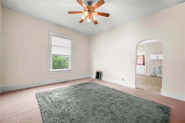 an empty room with windows and chandelier fan