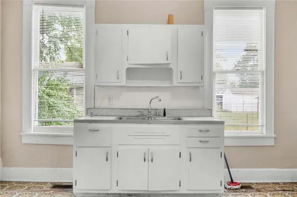 a view of an empty room with window and a kitchen