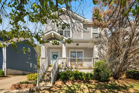 a front view of a house with plants and trees