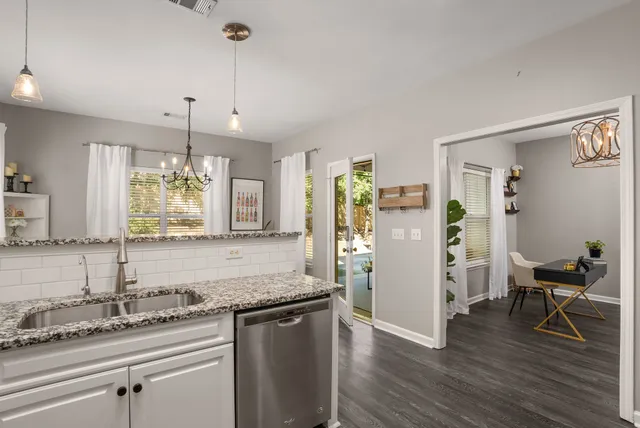 a kitchen with stainless steel appliances granite countertop a refrigerator a sink dishwasher a stove and white countertops with wooden floor