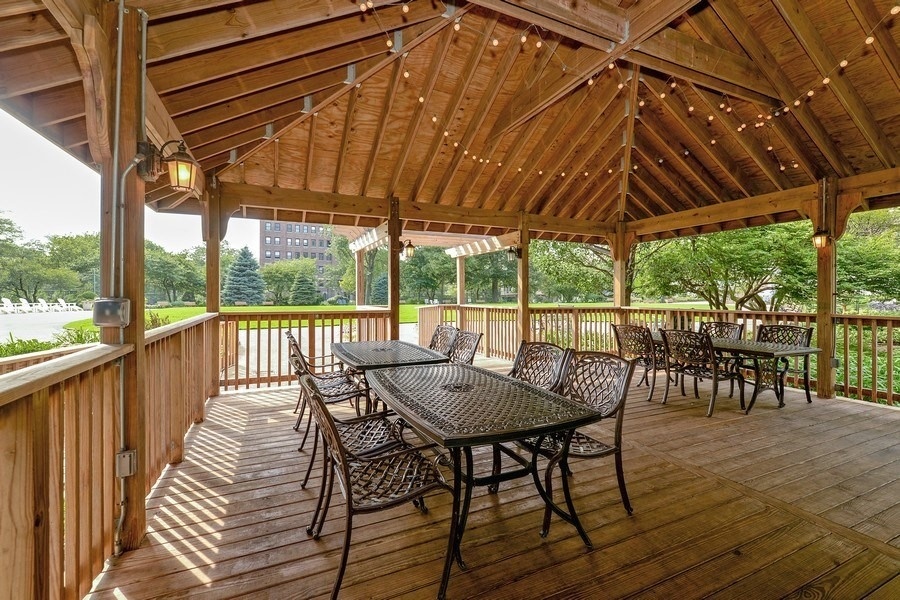 5555 North Sheridan Road, Unit 1908 Chicago, IL 60640 - Photo 9 of 13 a view of a patio with table and chairs under an umbrella with a small yard