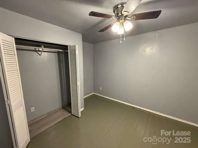 an empty room with windows and fan