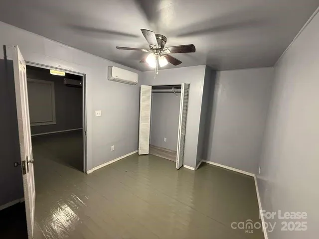 an empty room with closet and a ceiling fan