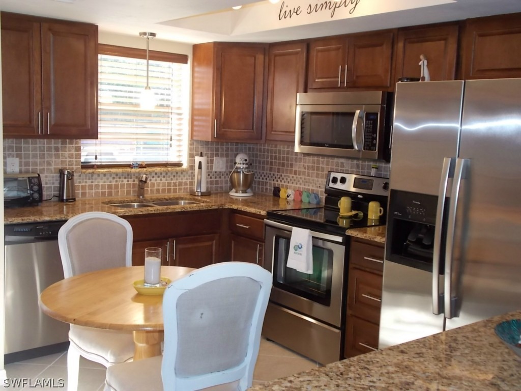 a kitchen with stainless steel appliances granite countertop a stove a sink a microwave a refrigerator and cabinets