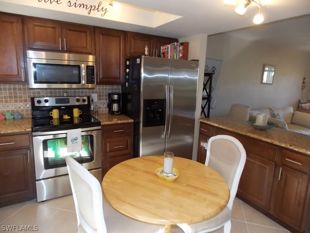 16881 Davis Road, Unit 813 Fort Myers, FL 33908 - Photo 3 of 25 a kitchen with stainless steel appliances granite countertop a refrigerator a stove a sink a dining table and chairs