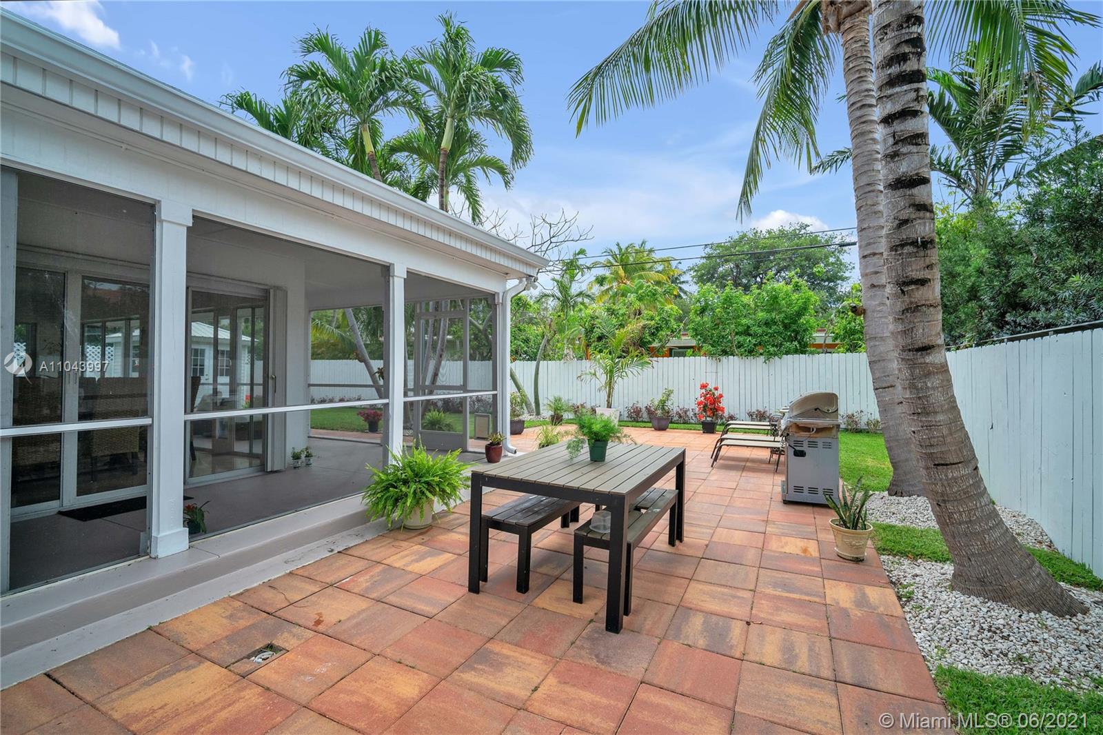 774 Fernwood Road Key Biscayne, FL 33149 - Photo 30 of 36 a backyard of a house with barbeque oven table and chairs