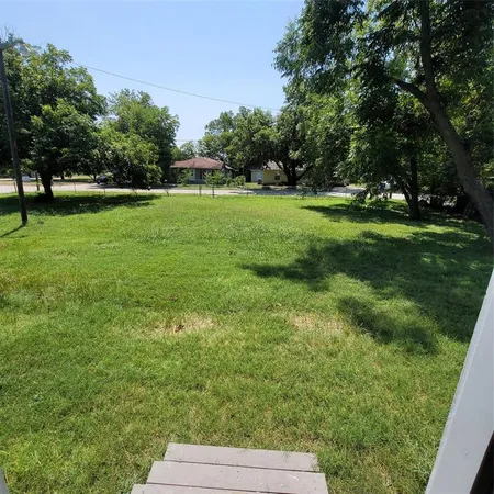 a view of grassy field with benches and trees all around