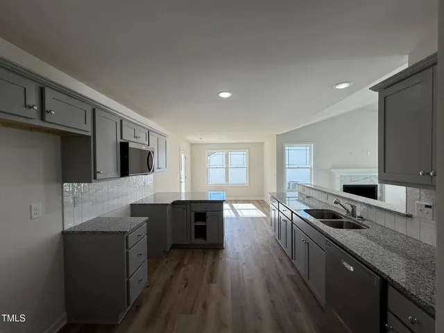 a kitchen with stainless steel appliances granite countertop a sink dishwasher stove and microwave with wooden floor