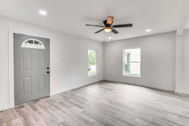 a view of an empty room with a window and wooden floor