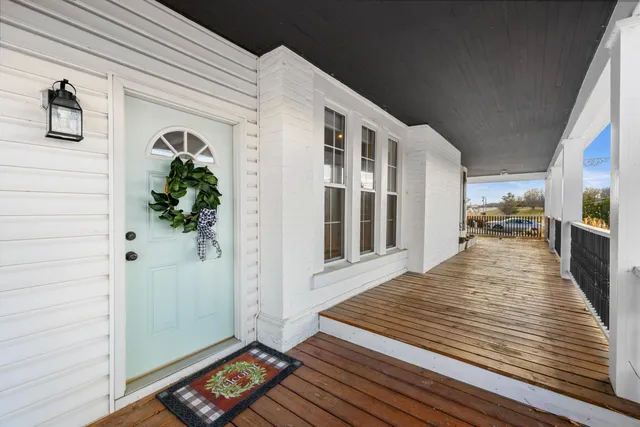 a view of an empty room with wooden floor a fireplace and a window