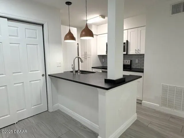 a kitchen with stainless steel appliances granite countertop a sink and a wooden floor