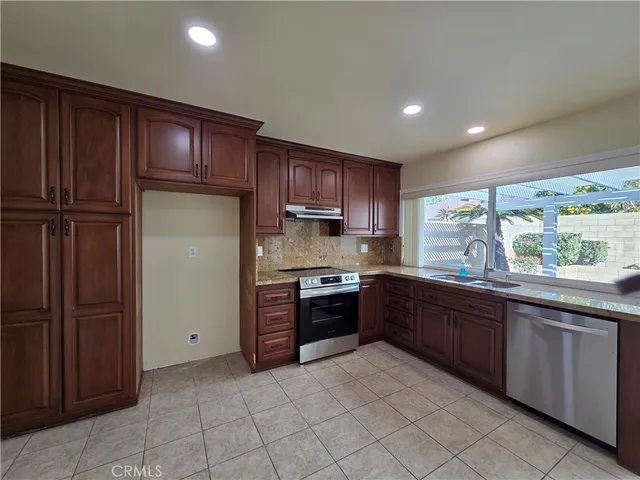 a large kitchen with stainless steel appliances granite countertop a refrigerator and a sink