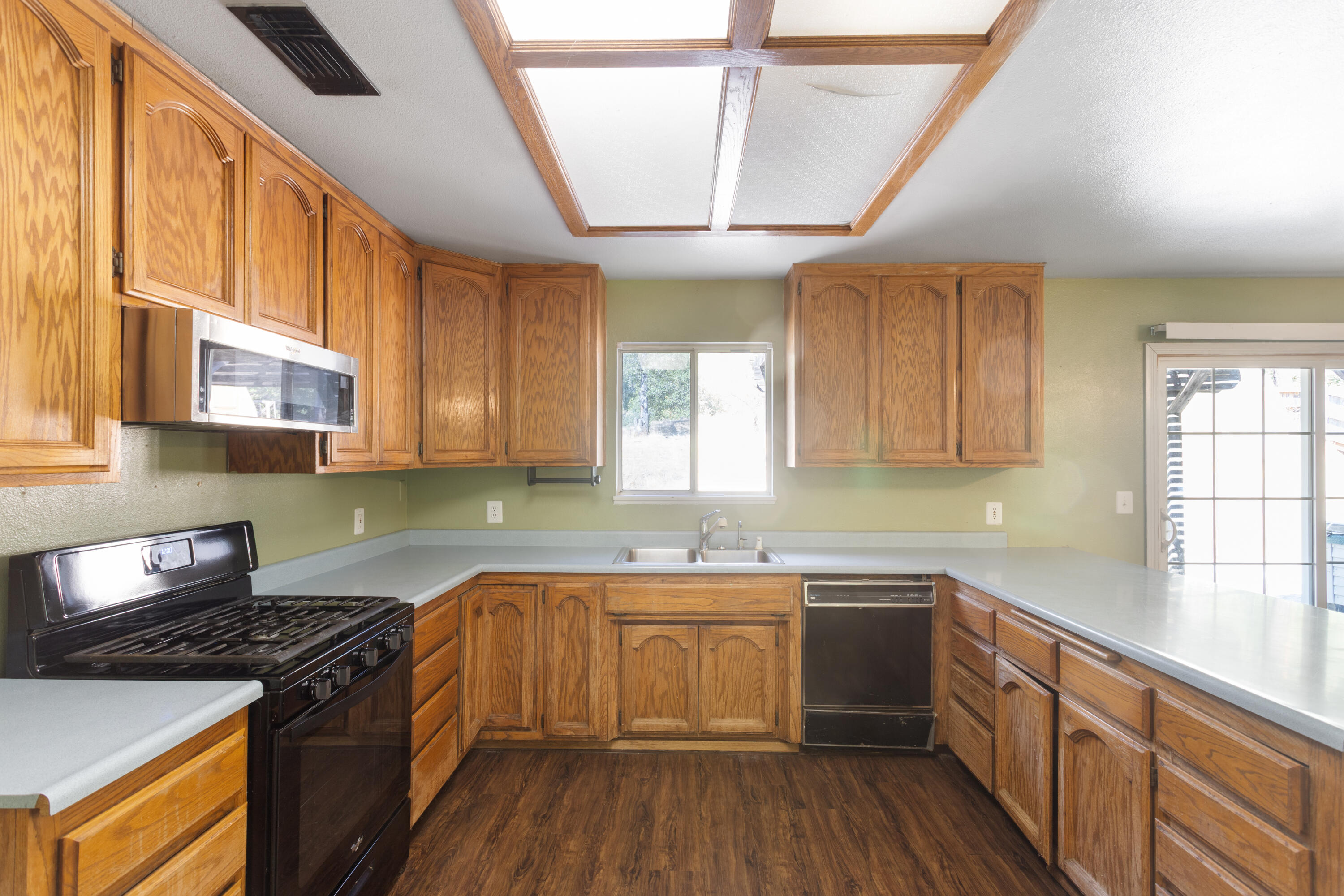 12656 Shalon Drive Redding, CA 96003 - Photo 8 of 21 a kitchen with stainless steel appliances granite countertop a stove a sink dishwasher and cabinets with wooden floor