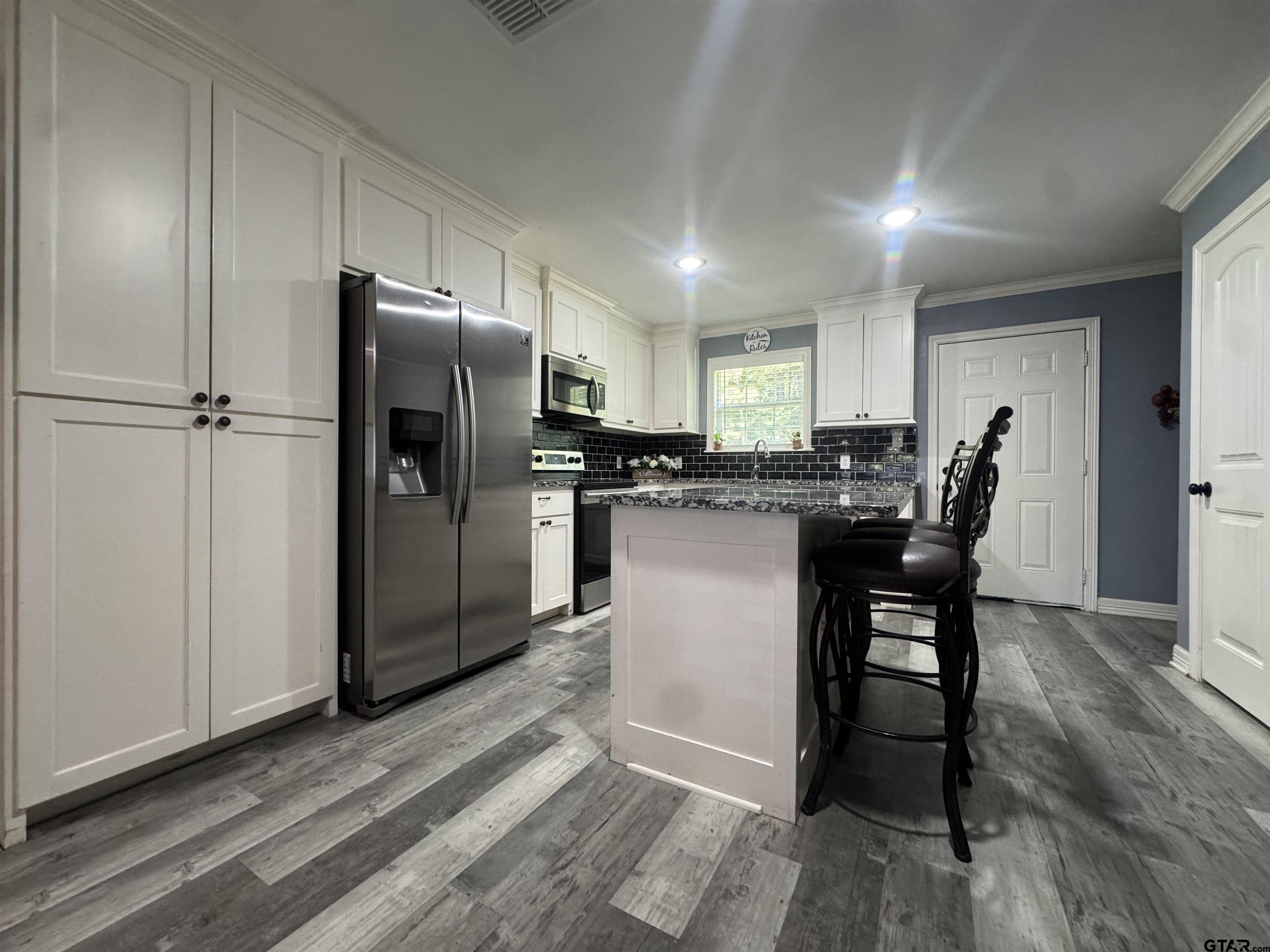 8261 County Road 381 Tyler, TX 75708 - Photo 7 of 24 a kitchen with stainless steel appliances a refrigerator a stove a sink and chairs