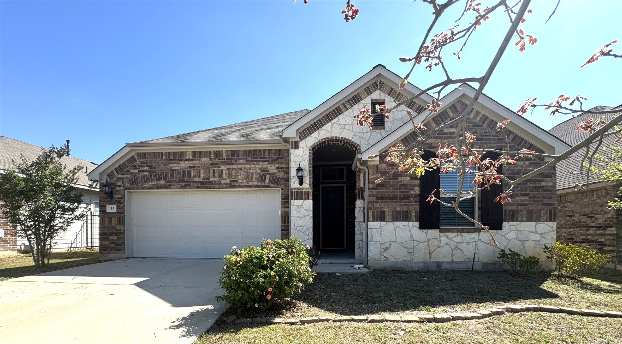 View of front of home featuring a garage, concrete driveway, stone siding, and brick siding