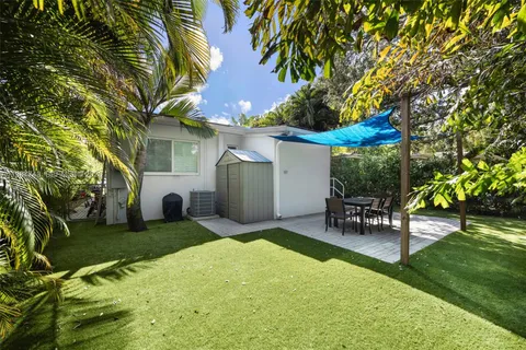 a view of a patio with table and chairs a barbeque and a large tree