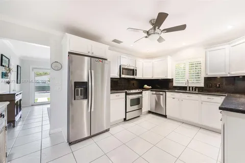 a kitchen with a refrigerator a sink and white cabinets