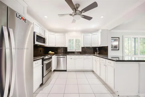 a kitchen with stainless steel appliances granite countertop a refrigerator sink and white cabinets