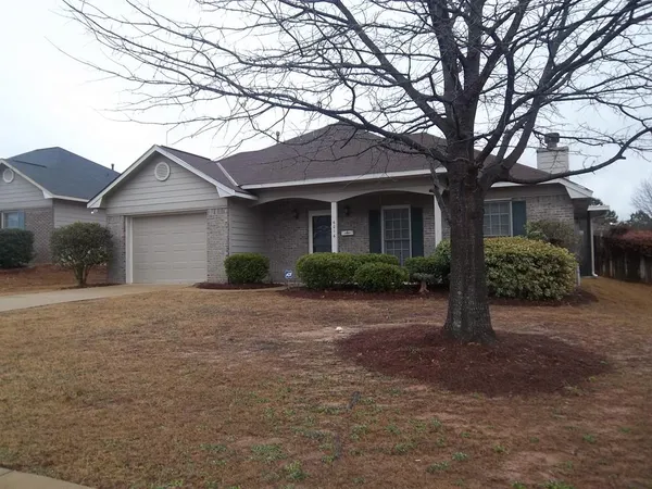 a front view of a house with a garden and trees