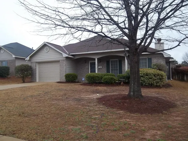 a front view of a house with a garden and trees