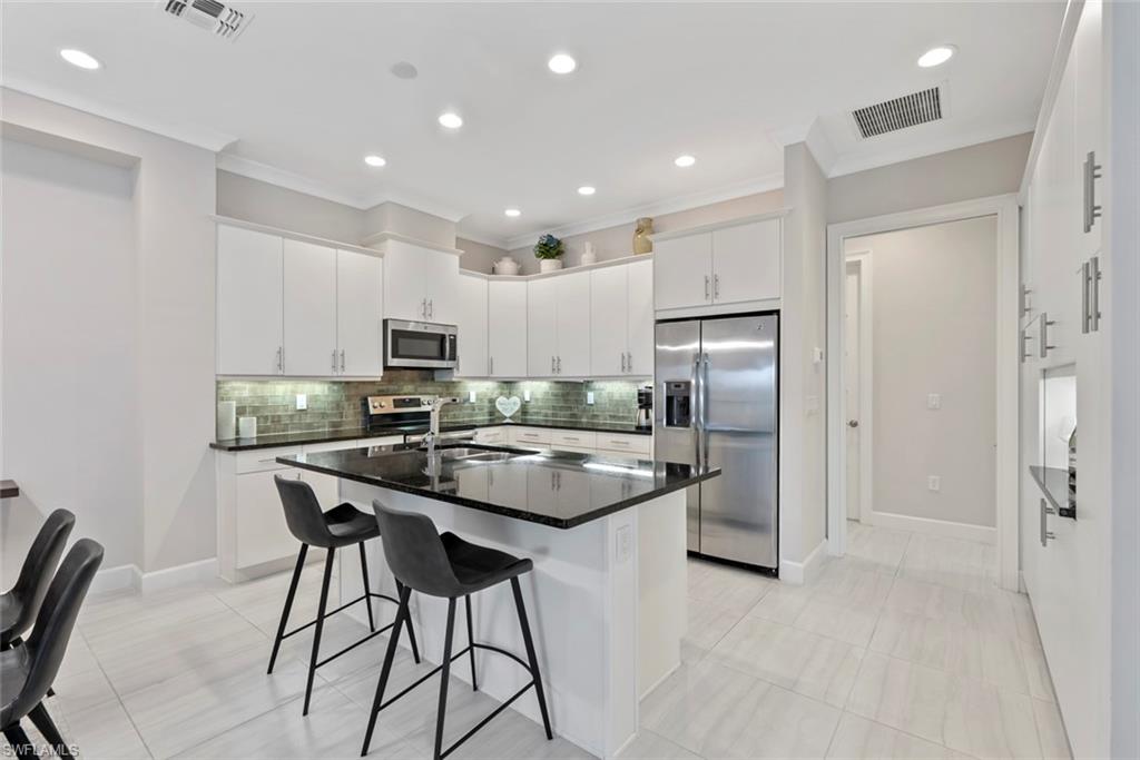 5716 Highbourne Drive Naples, FL 34113 - Photo 12 of 36 a kitchen with stainless steel appliances granite countertop a sink refrigerator and cabinets