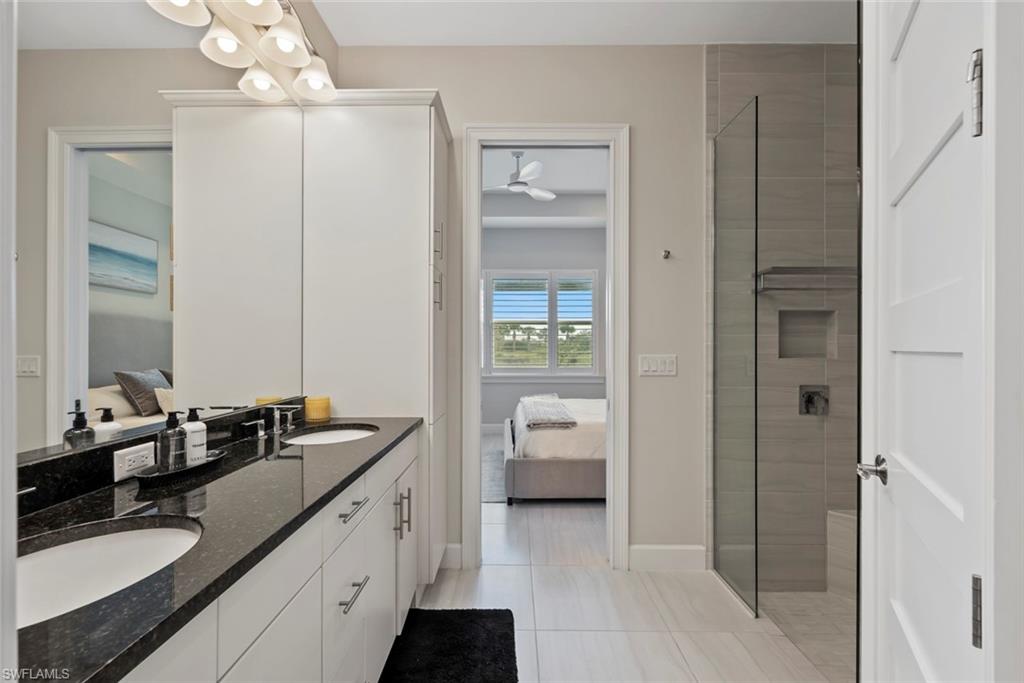 5716 Highbourne Drive Naples, FL 34113 - Photo 17 of 36 a en suite bathroom with a double vanity sink a mirror and a shower