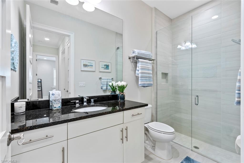 5716 Highbourne Drive Naples, FL 34113 - Photo 18 of 36 a bathroom with a granite countertop sink a toilet a mirror and shower
