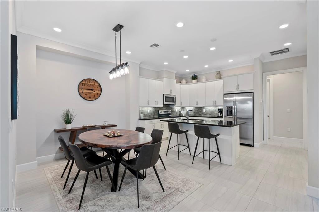 5716 Highbourne Drive Naples, FL 34113 - Photo 9 of 36 a kitchen with a dining table chairs and refrigerator