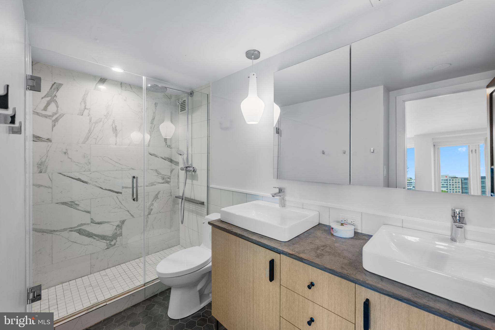 1101 3rd Street Southwest, Unit 315 Washington, DC 20024 - Photo 20 of 38 a bathroom with a granite countertop sink a toilet a mirror and shower