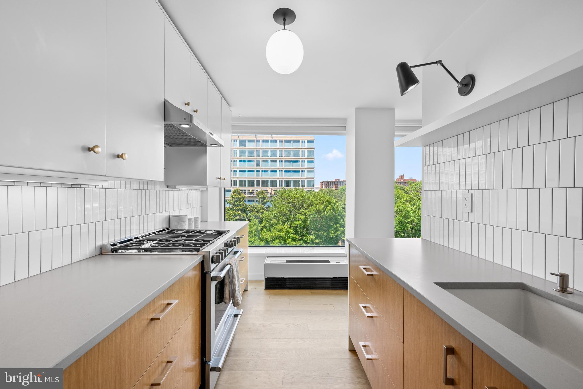 1101 3rd Street Southwest, Unit 315 Washington, DC 20024 - Photo 5 of 38 a kitchen with stainless steel appliances granite countertop a sink a stove and a wooden floors