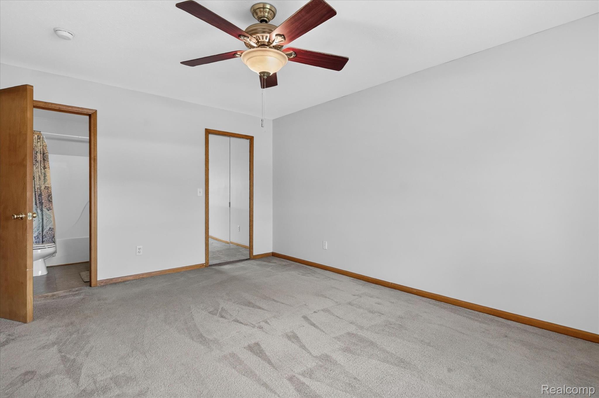 45720 Prairiegrass Court Belleville, MI 48111 - Photo 23 of 31 Carpeted interior space featuring a ceiling fan with light fixture, wood trim, and a mirrored closet door