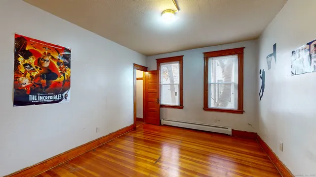 a view of an empty room with window and wooden floor