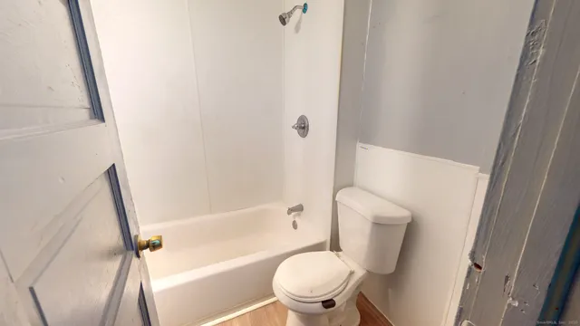 a white toilet sitting next to a bath tub