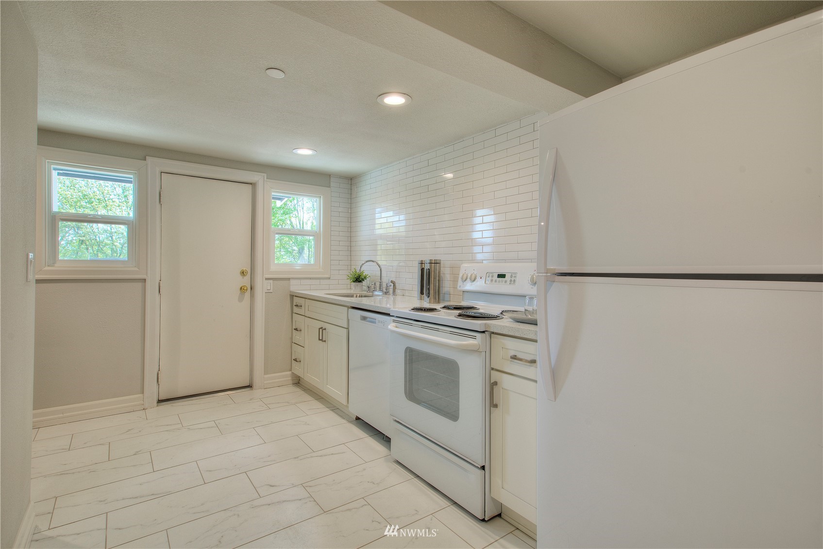 12222 Military Road South Seattle, WA 98168 - Photo 23 of 33 a kitchen with white cabinets and white appliances