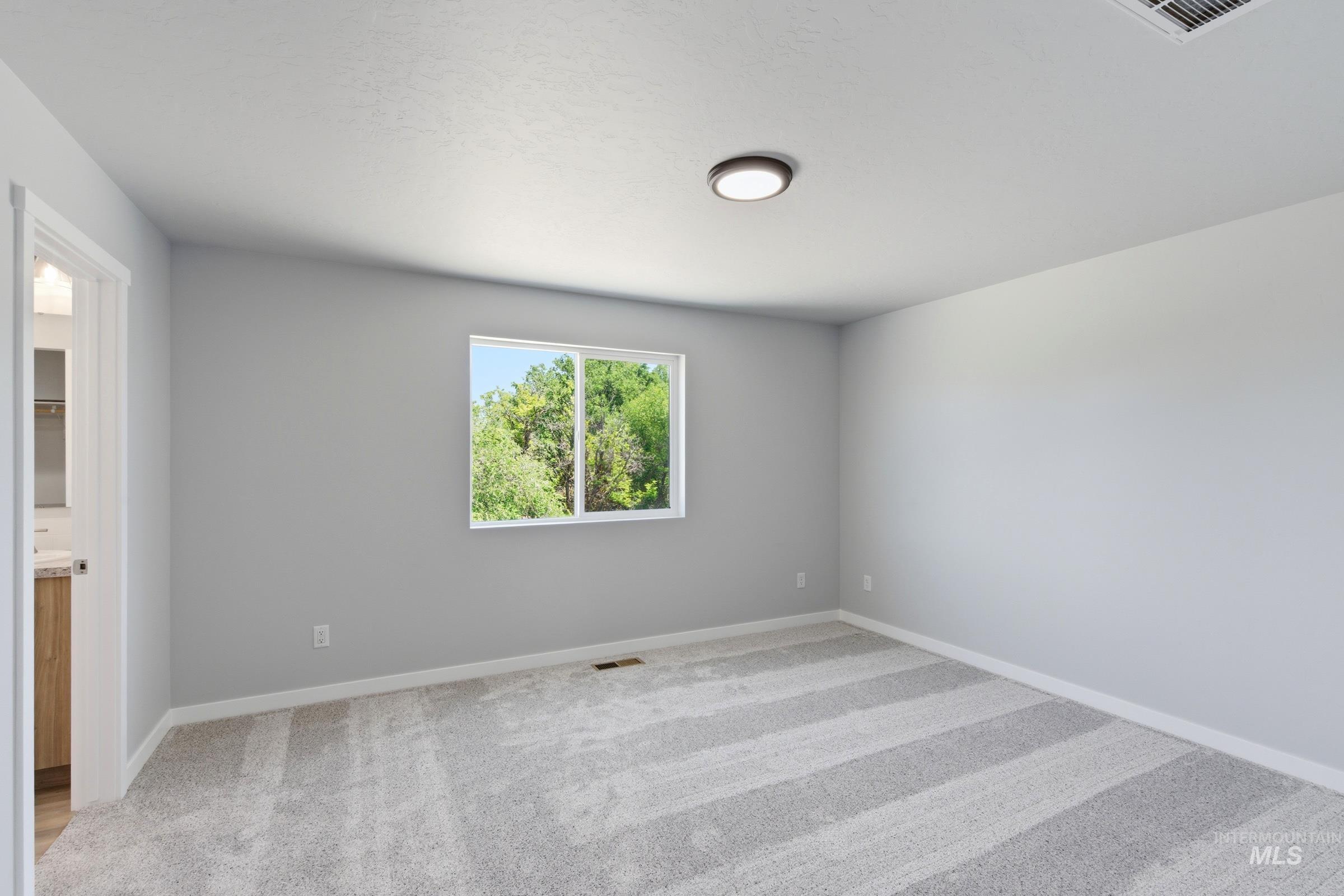 2374 West Fallon Loop Nampa, ID 83651 - Photo 19 of 24 Carpeted room with a rectangular window showcasing vibrant green foliage
