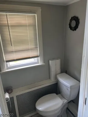 a white toilet sitting next to a window and a chair