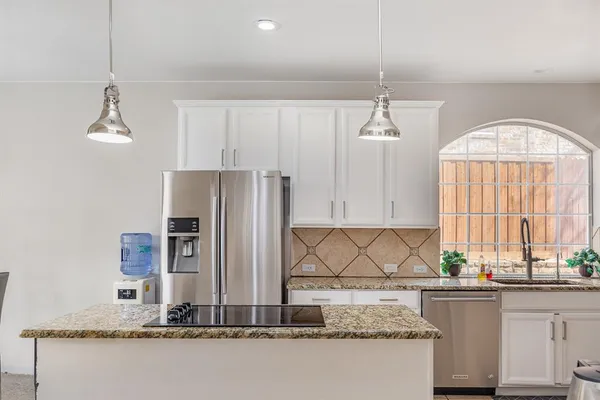 a kitchen with kitchen island granite countertop a sink a center island cabinets and a window